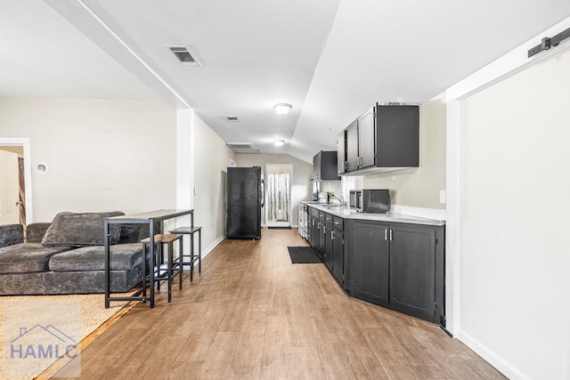 kitchen featuring light hardwood / wood-style flooring, black refrigerator, and vaulted ceiling