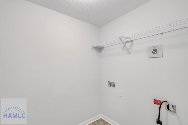 clothes washing area with hookup for an electric dryer, washer hookup, and a textured ceiling