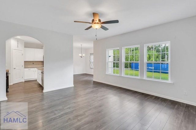 unfurnished living room featuring dark hardwood / wood-style floors and ceiling fan with notable chandelier