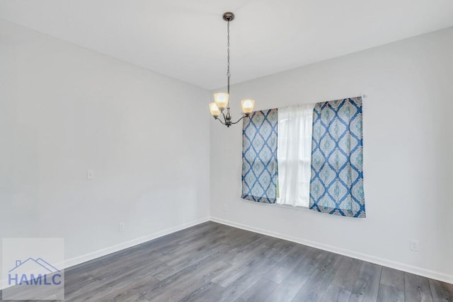 empty room with dark hardwood / wood-style floors and a notable chandelier