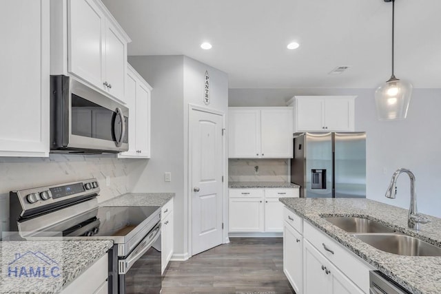 kitchen with decorative light fixtures, stainless steel appliances, white cabinetry, and sink