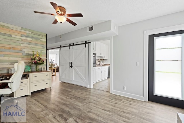 226 Topi Trl, Hinesville, GA 31313 - office area featuring a ceiling fan, a barn door, light wood-style floors, a textured ceiling, and a sink