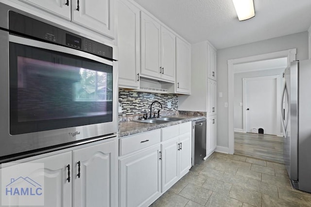226 Topi Trl, Hinesville, GA 31313 - kitchen with stainless steel appliances, a sink, white cabinetry, backsplash, and baseboards