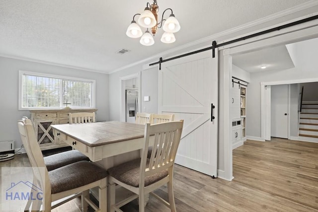 226 Topi Trl, Hinesville, GA 31313 - dining space featuring a barn door, crown molding, light wood-style floors, a chandelier, and a textured ceiling