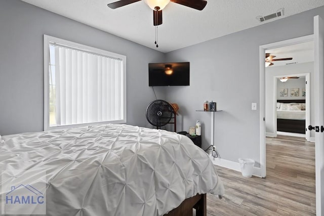 226 Topi Trl, Hinesville, GA 31313 - bedroom featuring wood finished floors, multiple windows, baseboards, ceiling fan, and a textured ceiling