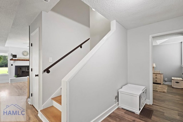 226 Topi Trl, Hinesville, GA 31313 - stairway featuring a textured ceiling, wood finished floors, baseboards, and a fireplace