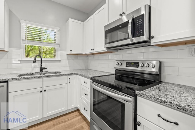 88 Windy Oaks Ct, Midway, GA 31320 - kitchen with stainless steel appliances, white cabinetry, light stone counters, and decorative backsplash