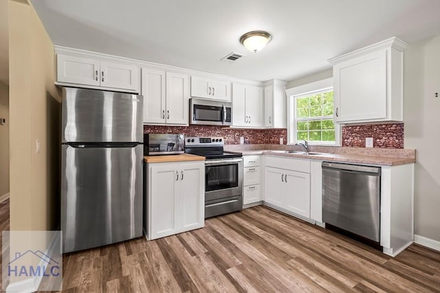 1869 Freedman Grove Rd, Fleming, GA 31309 - kitchen featuring appliances with stainless steel finishes, white cabinetry, light countertops, and wood finished floors