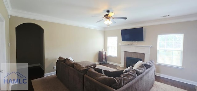 14 Cantebury Rd, Ludowici, GA 31316 - living room featuring crown molding, a ceiling fan, a tile fireplace, arched walkways, and dark wood-style flooring