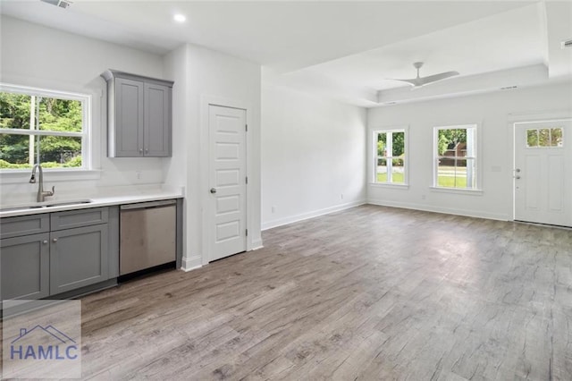 kitchen featuring gray cabinetry, sink, stainless steel dishwasher, and light hardwood / wood-style floors