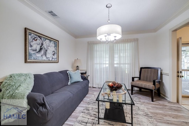 living room featuring crown molding, a chandelier, and light wood-type flooring