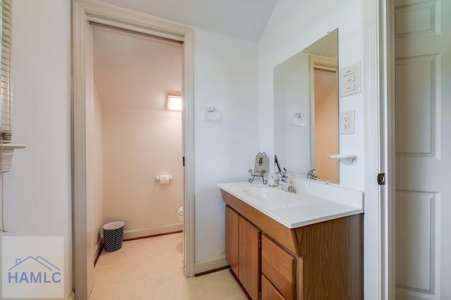 bathroom featuring vanity, toilet, and lofted ceiling