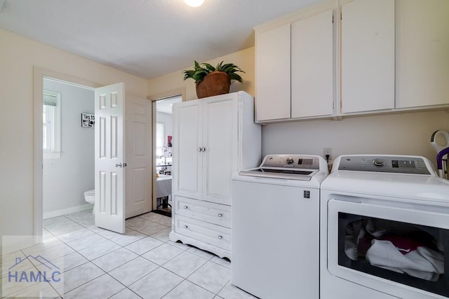 washroom featuring cabinets, independent washer and dryer, light tile patterned floors, and a healthy amount of sunlight