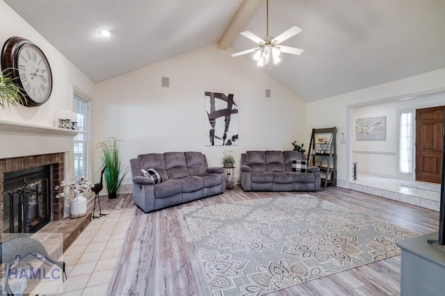 living room with beam ceiling, ceiling fan, a fireplace, and light hardwood / wood-style floors