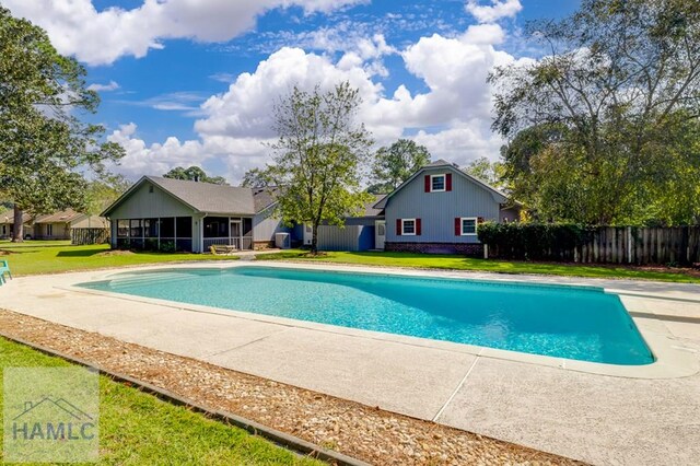 view of swimming pool with a yard and a sunroom