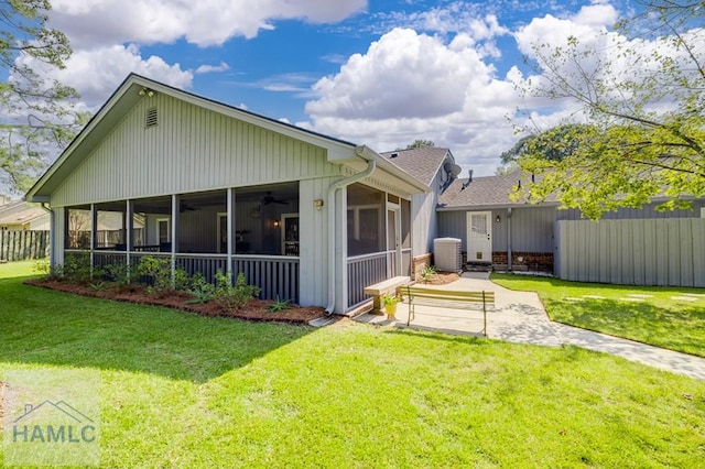 rear view of house with a lawn, central air condition unit, and a sunroom