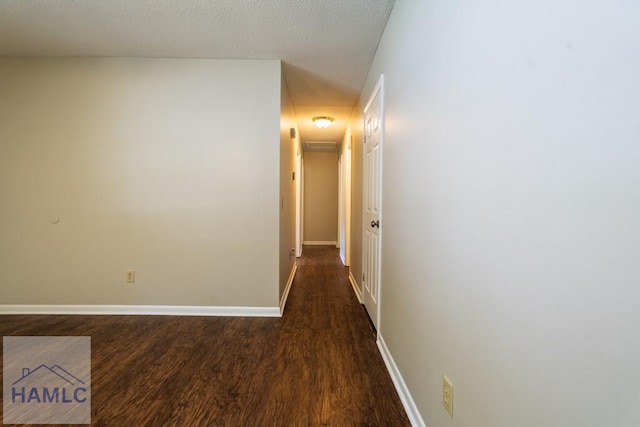 corridor with dark hardwood / wood-style flooring and a textured ceiling