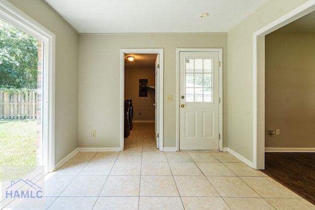 doorway with washer and dryer, a healthy amount of sunlight, and light tile patterned floors