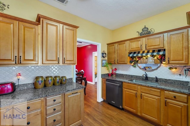 kitchen featuring tasteful backsplash, sink, dishwashing machine, and light hardwood / wood-style flooring