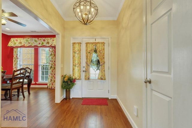 entryway with crown molding, ceiling fan with notable chandelier, and hardwood / wood-style floors