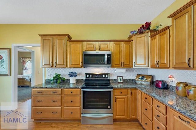 kitchen featuring backsplash, stainless steel appliances, and dark stone countertops