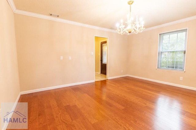 spare room with hardwood / wood-style floors, crown molding, and a notable chandelier