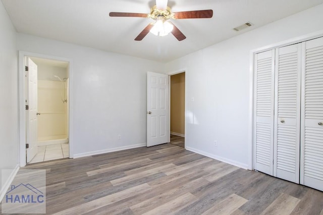 unfurnished bedroom featuring ceiling fan, a closet, ensuite bathroom, and light hardwood / wood-style floors