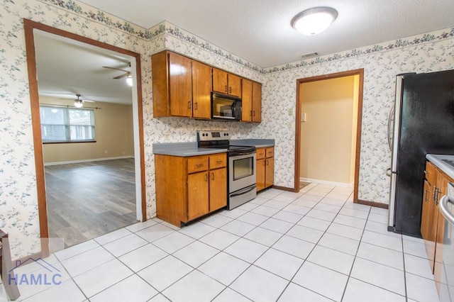 kitchen with ceiling fan, a textured ceiling, appliances with stainless steel finishes, and light hardwood / wood-style flooring