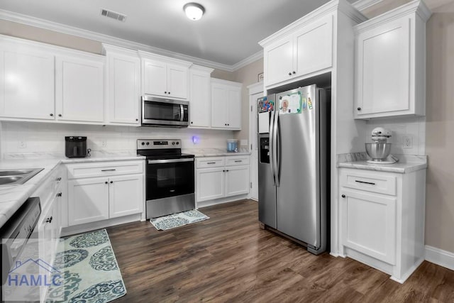 kitchen featuring dark hardwood / wood-style floors, white cabinets, decorative backsplash, stainless steel appliances, and crown molding