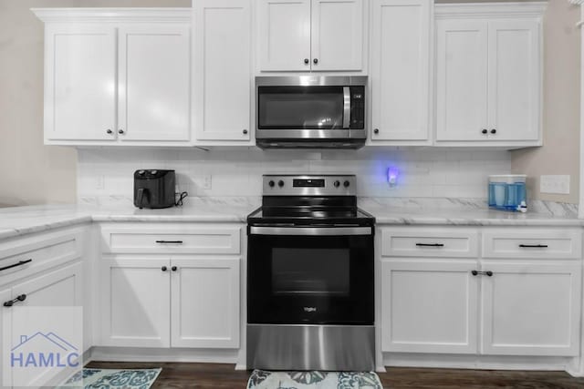 kitchen with white cabinetry, appliances with stainless steel finishes, light stone counters, and decorative backsplash