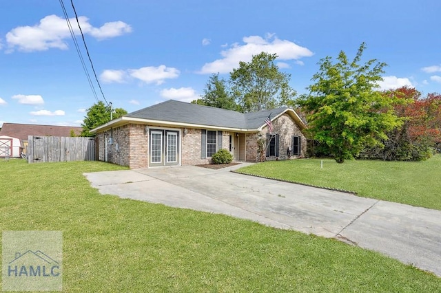 ranch-style house with fence, a front lawn, brick siding, french doors, and driveway