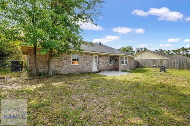 rear view of house with a patio, a fenced backyard, a lawn, and brick siding