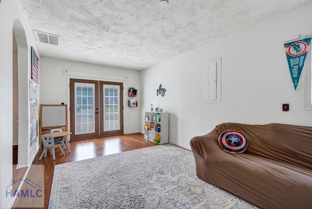 sitting room with arched walkways, visible vents, french doors, and wood finished floors