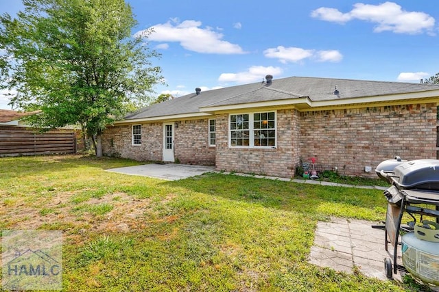 back of house featuring fence, a patio, a lawn, and brick siding
