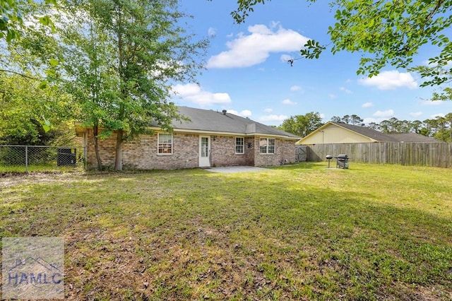back of property with a lawn, brick siding, a fenced backyard, and a patio area