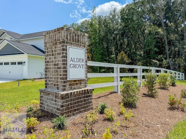 community sign with fence, a lawn, and an attached garage