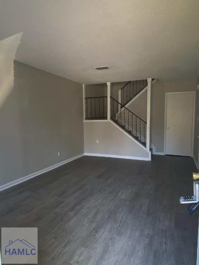 unfurnished living room with dark wood-type flooring and a textured ceiling