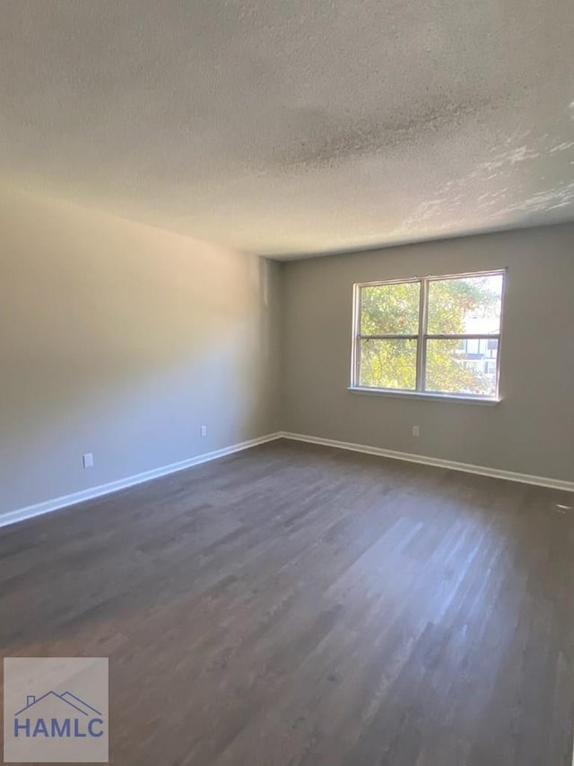 empty room featuring dark hardwood / wood-style flooring and a textured ceiling