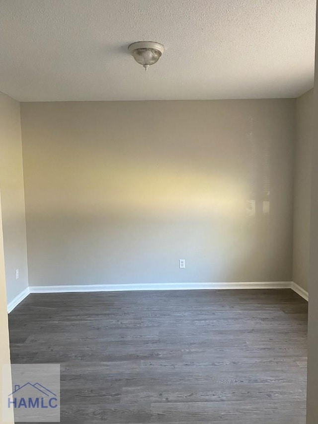 spare room featuring dark hardwood / wood-style floors and a textured ceiling