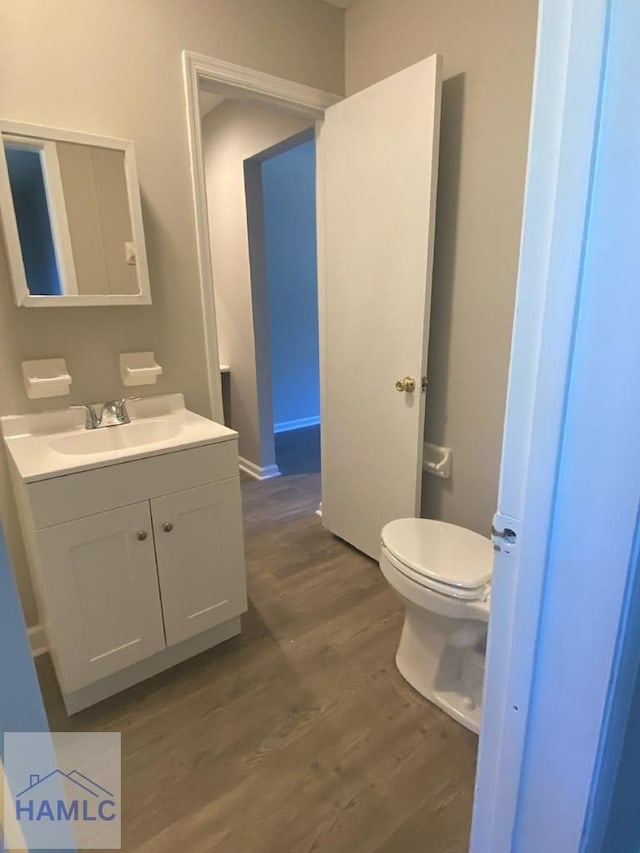 bathroom with vanity, toilet, and hardwood / wood-style floors