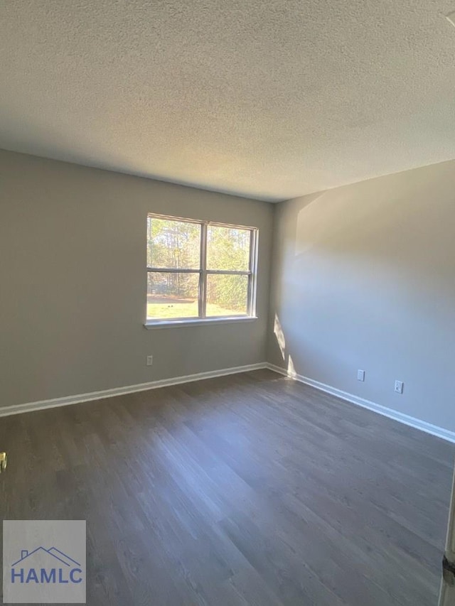 unfurnished room with dark hardwood / wood-style floors and a textured ceiling