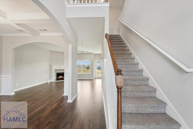 7 Summerhill Dr, Ludowici, GA 31316 - staircase featuring a warm lit fireplace, wood finished floors, beamed ceiling, ornamental molding, and coffered ceiling