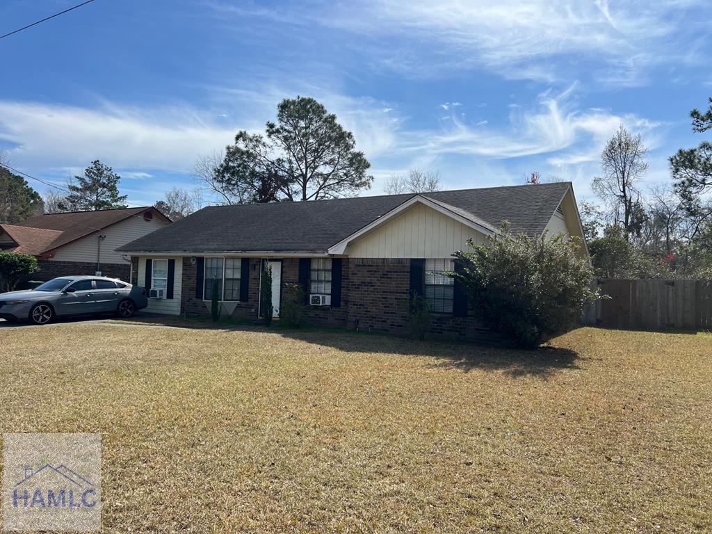 ranch-style home featuring brick siding, a front yard, and fence