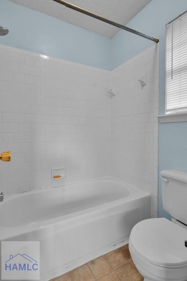 bathroom with tile patterned flooring, a textured ceiling, toilet, and tiled shower / bath