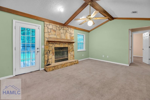 unfurnished living room featuring carpet, a textured ceiling, ceiling fan, lofted ceiling with beams, and a fireplace