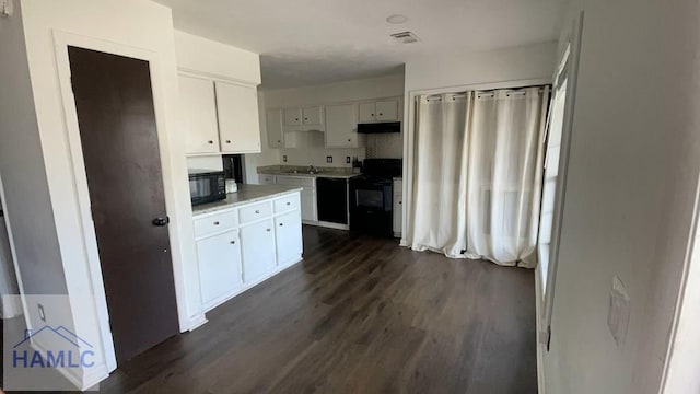 kitchen with white cabinets, dark wood finished floors, under cabinet range hood, black appliances, and a sink