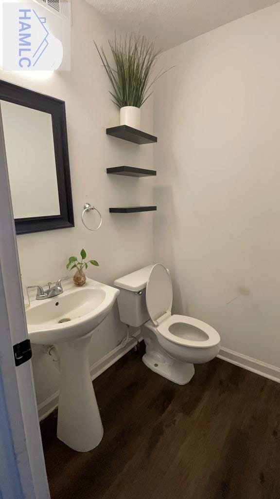 half bath featuring baseboards, toilet, and wood finished floors