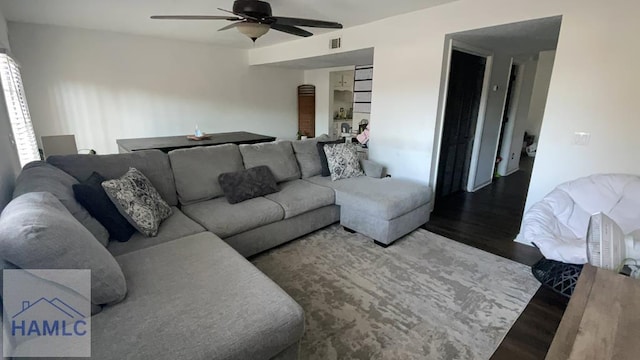 living area with a ceiling fan, visible vents, and wood finished floors