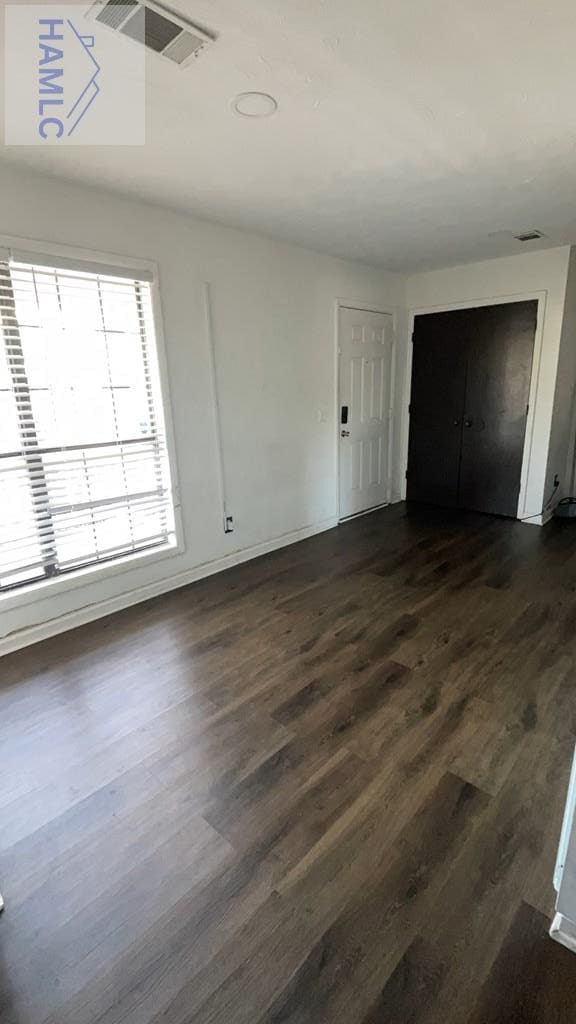 unfurnished bedroom featuring visible vents and dark wood-type flooring