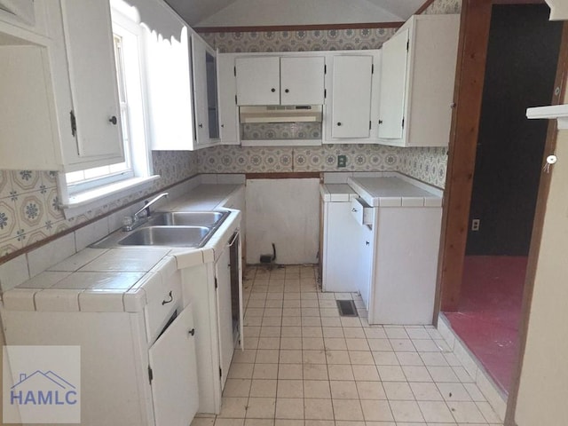 5927 Yellow Bluff Rd, Blackshear, GA 31516 - kitchen featuring under cabinet range hood, tile countertops, light tile patterned floors, decorative backsplash, and white cabinets